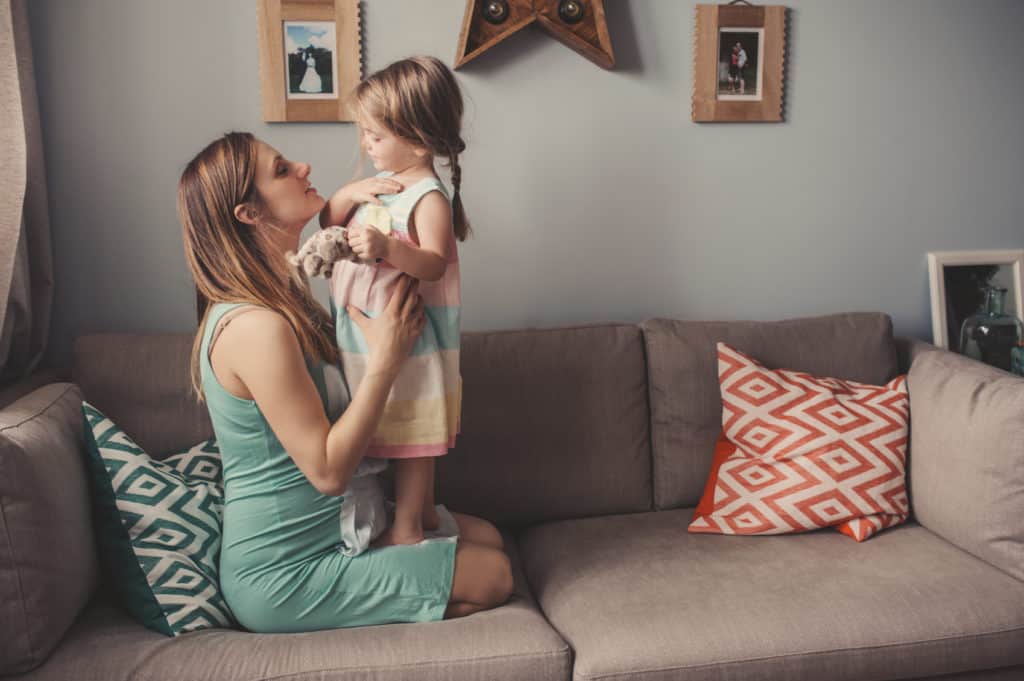 happy mother and toddler daughter playing together at home